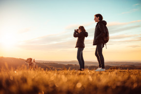 mother daughter standing top mountain with dog using binoculars